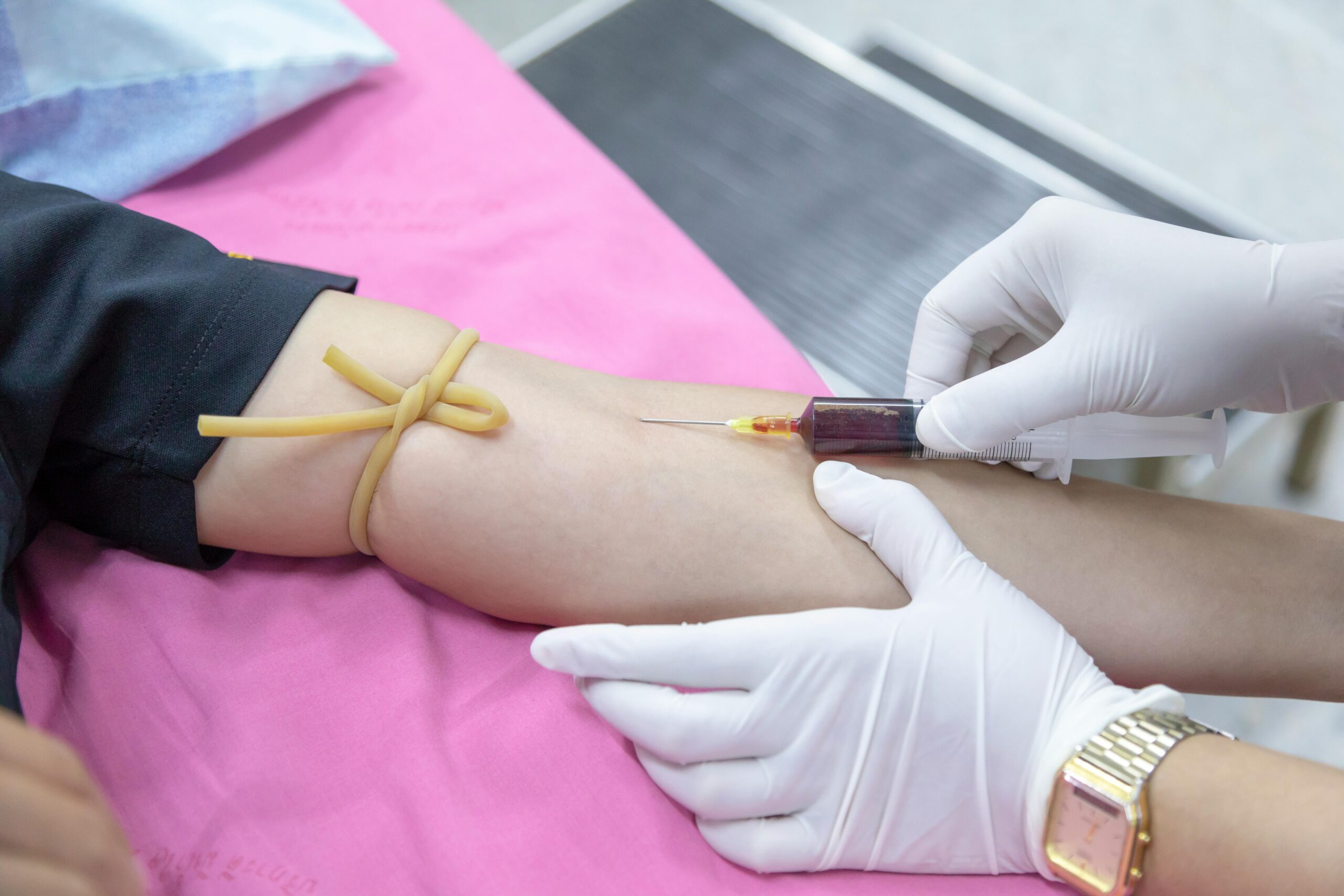 A medical professional takes a blood sample from a patient for testing.