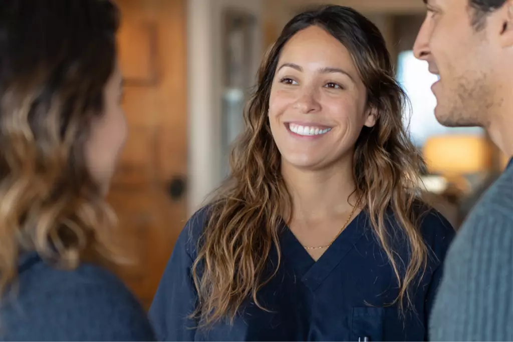 Friendly recovery center staff member warmly greeting two new clients inside a welcoming outpatient facility, symbolizing compassion and trust