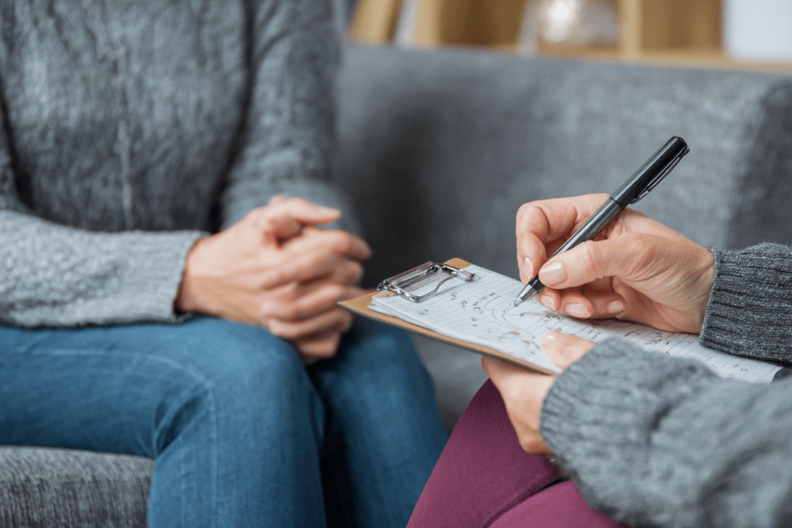 Therapist and client mapping the thought–feeling–behavior cycle on a notepad.